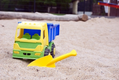 Sandkasten mit Spielzeugauto und Schaufel