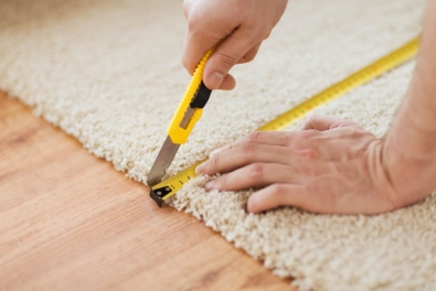 Handwerker schneidet Teppichboden mit einem Messer